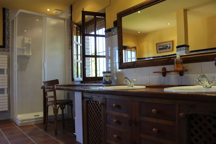 Interior · baño con ducha, dos lavabos y ventana.