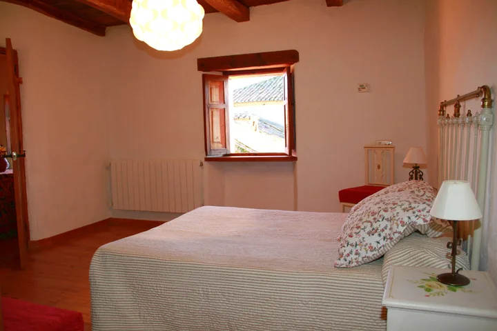 Interior · dormitorio matrimonial con ventana y luz natural.